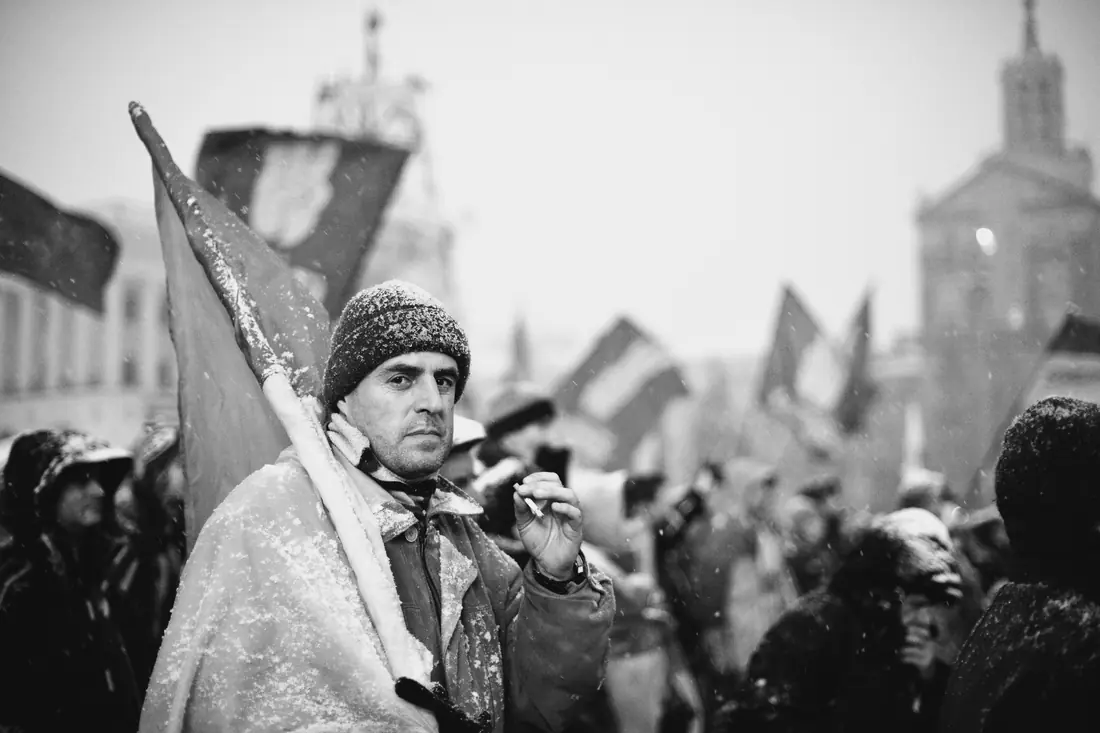 Учасник протестів, загорнутий в український прапор, стоїть під снігом на Майдані Незалежності